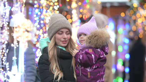 Mom and her little daughter are walking at the street Christmas market