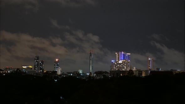 Timelapse of a cloudy sky at night above some buildings in Bangkok, Thailand.