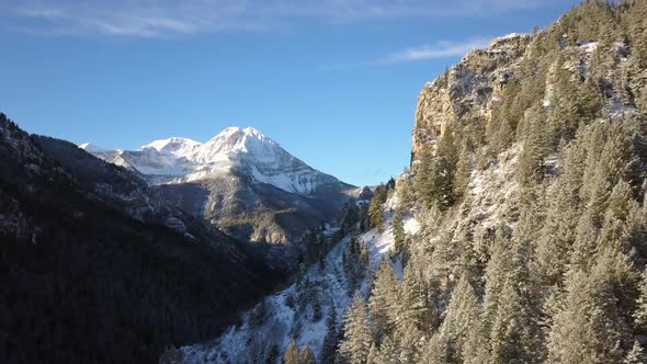 Flying along snow covered hillside over canyon