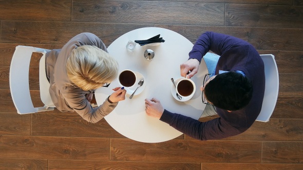 Happy young couple drinking coffee and talking in coffee shop