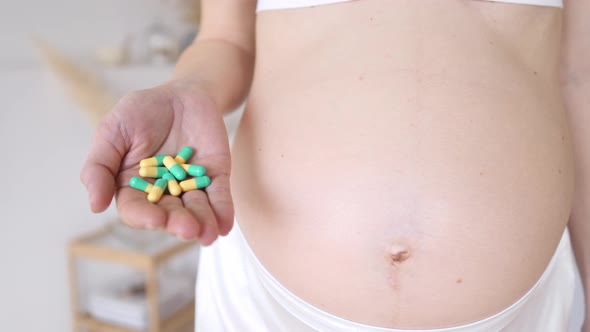 Belly Of Pregnant Woman And Vitamin Pills In The Hand