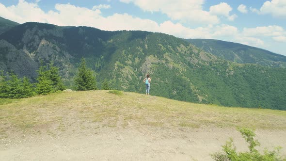 Young Woman Hiker Standing on the Mountain Edge and Looking at the Deep Valey Below