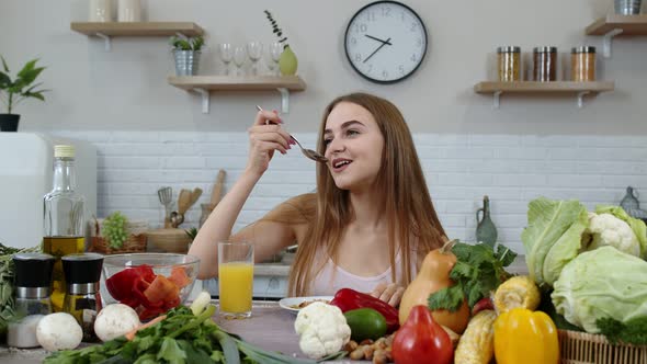 Lovely Girl Eating Raw Sprouts Buckwheat with Nuts in Kitchen with Fresh Vegetables and Fruits