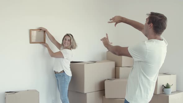 Married Couple Choosing Place on Wall for Picture Frame