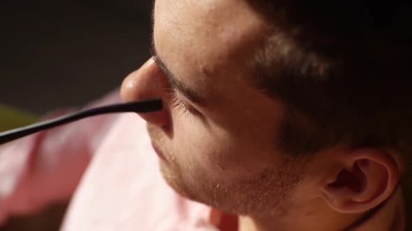 Closeup Highangle View of Bearded Handsome Man Put One Glasses and Looking Forward in Dark Room