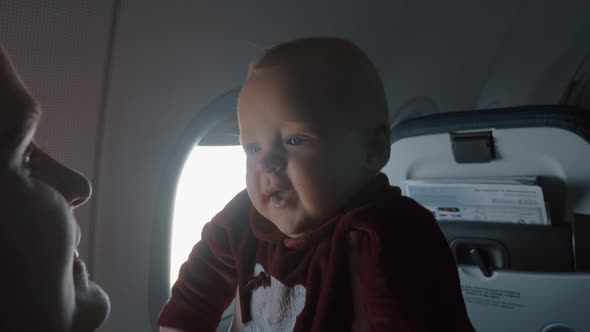 Happy baby daughter in mothers arm Family traveling by plane