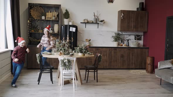 Mom and Son Run Fun Slip Around Table in Santa New Year Hats