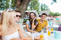 A company of good-looking friends laughing and drinking yellow cocktails and socialising at the - PhotoDune Item for Sale