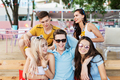 A company of good-looking friends wearing sunglasses laughing and drinking yellow cocktails and - PhotoDune Item for Sale