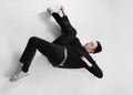 Freestyle dancer dressed in black jeans, sweatshirt, hat and gray sneakers is dancing lying on the - PhotoDune Item for Sale