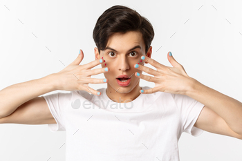 People, lgbtq and beauty concept. Close-up of beautiful gay man with glitter on face, showing nail / Photodune, Misc