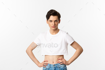 Handsome androgynous man in crop top looking confident at camera, holding hands on waist. Lgbtq / Photodune, Misc