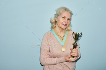 trophy and looking at camera while standing against blue background, copy space