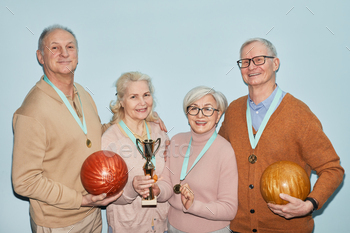 g trophy and bowling balls while standing against blue background, shot with flash