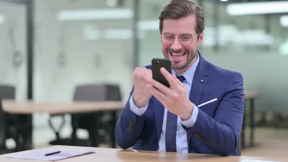 Young Businessman Celebrating Success on Smartphone