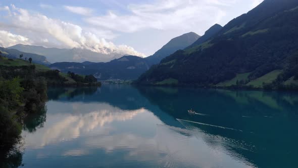 Scenic aerial view of fishing boat pulling net on Lungernersee lake, Switzerland