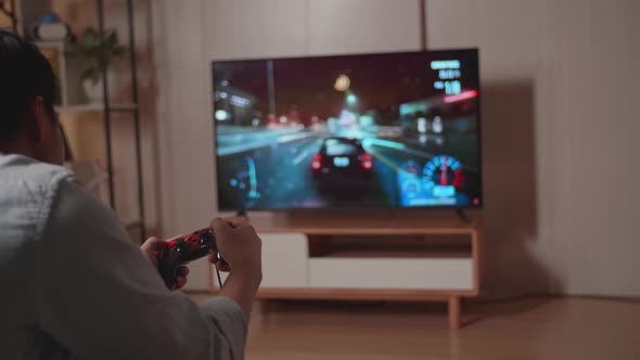 Young Man Gamer Playing Car Race Game On Tv At Home