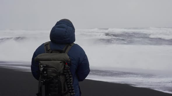 Photographer Adjusting Camera On Black Sand Beach