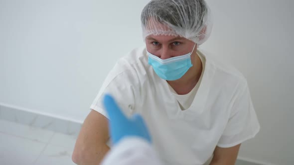 Portrait of Sad Tired Doctor Sitting on Floor Leaning at Wall Taking Hand of Colleague Standing Up