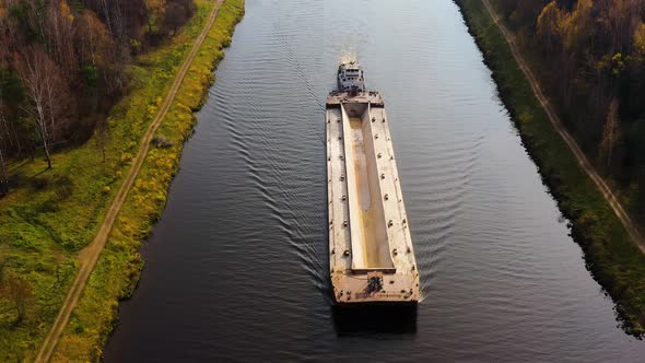 River Tugboat Moves Cargo Barge on the River. Autumn Landscape.