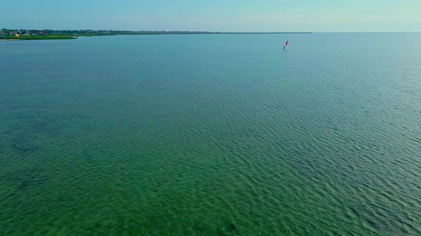 Drone Flying Over the Sea Towards the Windsurfer