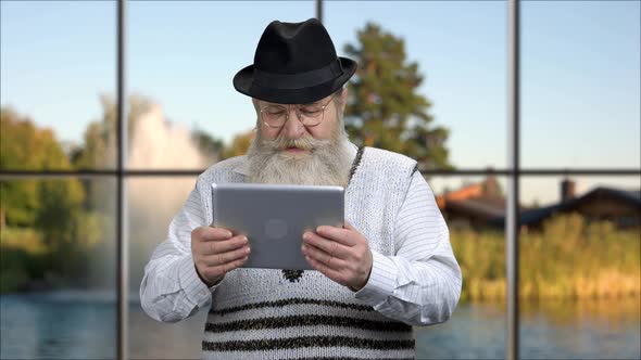 Funny Senior Man Playing Game on Tablet Pc.