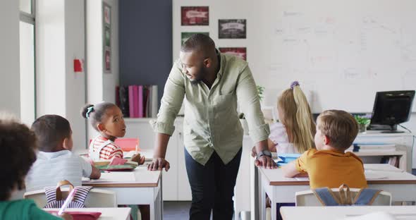 Video of happy african american male teacher during lesson with class of diverse pupils