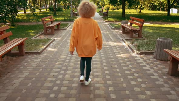 Blonde Female Walks in City Park