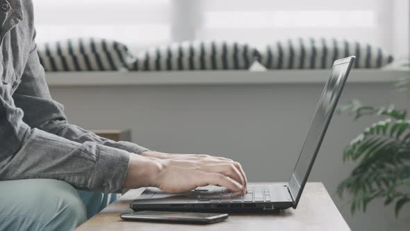 An Unrecognizable Man is Typing Very Quickly on a Laptop Keyboard