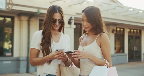 Two beautiful shopper girls text their friends about their day