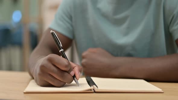 Close Up of African Man Writing in Notebook