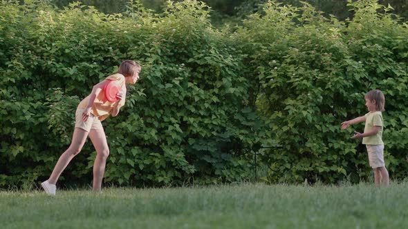 Mother and Son Play Frisbee on Grass Lawn