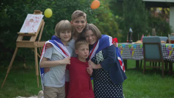 Portrait of Happy Kids Wrapping in British Flag Posing on Backyard Outdoors