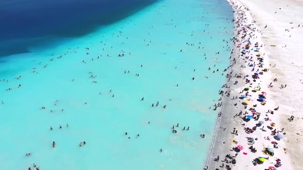 People Swim on Vacation in the White Sandy Beach of the Clear Tropical Turquoise Light Blue Sea