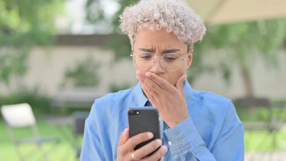 Portrait of Young African Woman Reacting to Loss on Smartphone