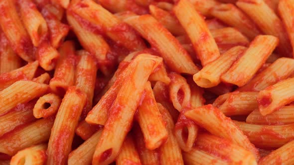 Pasta penne with tomato sauce in pan, rotation