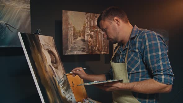 The Artist Paints a Picture with Oil Paints in His Studio