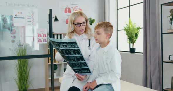 Doctor Talking with Her Teen Boy-Patient and Explaining Results of His Lungs X-ray