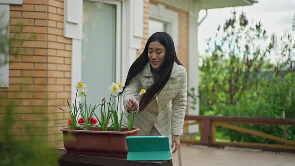 Slim Young Asian Woman Walking to Tablet on Porch Waving at Webcamera and Smelling White Tender