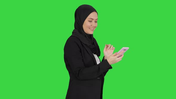 Muslim Girl in Hijab Using Smartphone To Send Voice Messages on a Green Screen, Chroma Key.