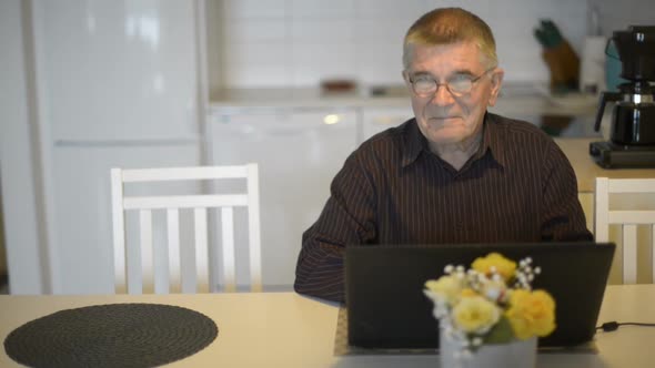 Senior Man Using Laptop and Giving Thumbs Up in the Dining Room