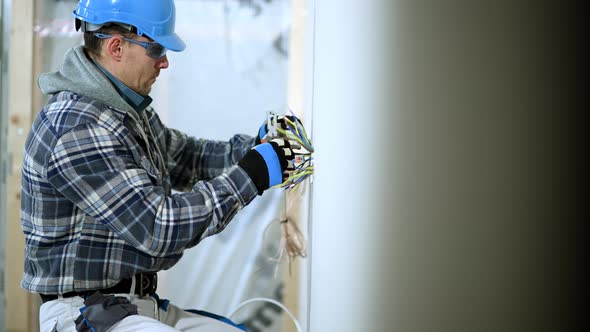 Man in Mid 30s Separates Wires In New Electric Outlet.