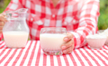 A girl in a red plaid shirt holds out a glass of milk - PhotoDune Item for Sale