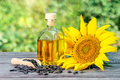 Bottle of sunflower oil and sunflower flowers with seeds on wooden table - PhotoDune Item for Sale