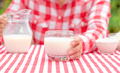 Girl in red plaid shirt holds out glass of fresh milk - PhotoDune Item for Sale