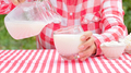 Woman pours milk from jug into glass - PhotoDune Item for Sale