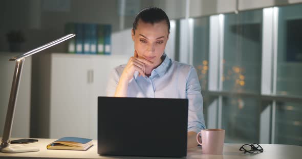 Young Businesswoman Working on Laptop in Office in Evening
