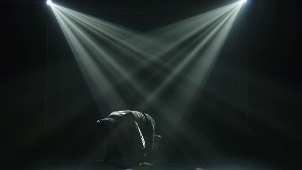 Breakdancing Movements in a Dark Studio Under the Spotlights. Silhouettes of a Dancing Man in Slow