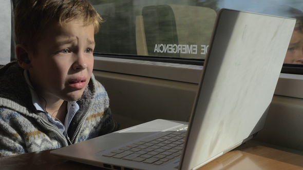 Child traveling by train and watching movie on laptop