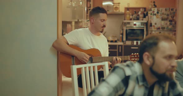 Young Man Plays Guitar to Friends